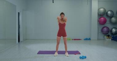 Girl athlete performing a dynamic rotation exercise with bent arms in a gym studio video