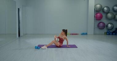 Girl athlete performs seated piriformis stretch in gym to enhance flexibility and prevent injury during training session video
