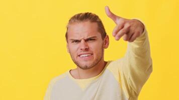 A young man with light hair and a confident demeanor gestures playfully while wearing a casual shirt. His expression is animated, conveying a sense of fun and liveliness. video