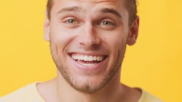 A young man of mixed heritage, featuring a cheerful smile, stands confidently in front of a vibrant yellow backdrop. His friendly expression radiates positivity and warmth, typical of Gen Z. video