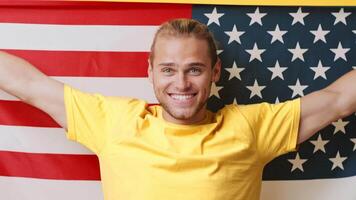 A young man with a joyful expression stands proudly in front of an American flag. video