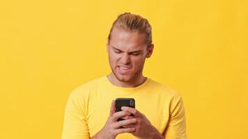 A young man with light hair uses his smartphone, displaying a focused expression. The bright yellow backdrop adds energy to the scene, emphasizing the modern lifestyle of Gen Z. video