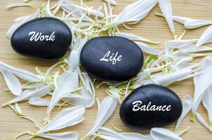 Top view of Work Life Balance text on zen stones with white color flower petals photo