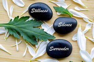 Top view of Zen stones with Stillness, Silence and Surrender text. Representing inner peace of life photo