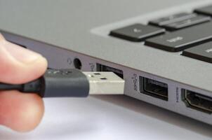 USB being plugged into laptop highlighting risk of unauthorized data transfer or malware photo