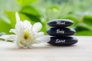 Mind, Body and Spirit text on zen stones with white color flower and blur background photo