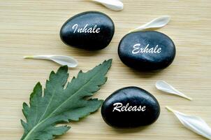 Inhale, Exhale and Release text on zen stones surrounded by flower petals. Inner peace concept photo