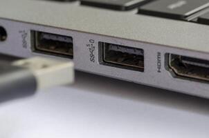 Hand inserting USB into laptop port demonstrating threat from unknown external devices photo
