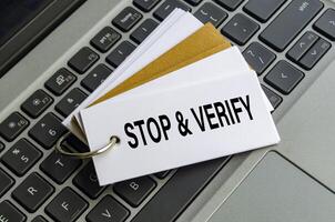 STOP AND VERIFY note on keyboard encouraging users to think before they act online photo