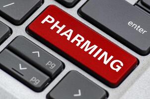 Pharming text on laptop keyboard indicating where users can be redirected unknowingly to fake websites photo