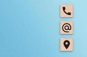 Contact Us background. Telephone, envelope letter and location icons on wooden blocks with copy space blue background photo