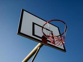 Low angle view of basketball hoop and backboard against clear blue sky background photo
