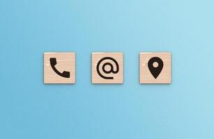 Contact Us concept. Telephone, envelope letter and location icons on wooden blocks on blue background photo