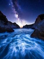 A view of the milky way over the ocean between rocks with waves crashing in the foreground at night photo
