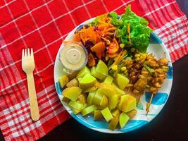 Fresh healthy, vegetable salad, of cheese, tomato, carrot, potato, green pepper and green basil leaves, top view A plate of food with a fork on it. photo