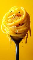 Delicious spaghetti served on a fork. A fork holds a twirl of yellow spaghetti topped with black pepper, set against a vibrant yellow backdrop. photo