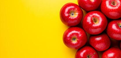 Bright red apples on yellow background. A cluster of shiny red apples rests against a vibrant yellow backdrop, showcasing their fresh and appetizing appearance. photo