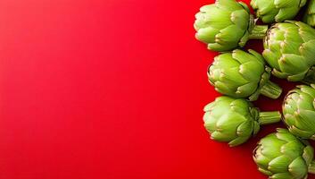 Artichokes on red backdrop. Bright green artichokes are arranged on a striking red background, creating a visually appealing display of freshness. photo