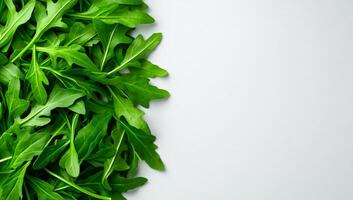 Fresh arugula leaves on light background. Bright green arugula leaves arranged neatly on a pale surface, showcasing their vibrant color and texture. photo