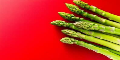 Green asparagus on red bg. Bright green asparagus stalks arranged neatly against a vibrant red backdrop, showcasing their fresh appearance. photo