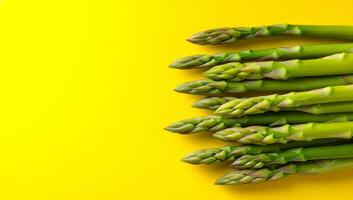 Asparagus on a bright backdrop. Green asparagus spears are neatly arranged against a bright yellow background, highlighting their fresh appearance. photo