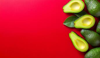 Fresh avocados arranged on a red surface. Halved avocados with green flesh placed next to whole avocados on a vibrant red backdrop, highlighting their texture. photo