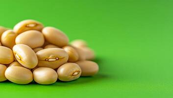Fresh beans on green. A pile of light-colored beans rests on a vivid green surface, showcasing their smooth texture and natural sheen. photo