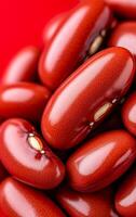 Red kidney beans on a bright surface. Close-up of shiny red kidney beans on a vibrant red background, highlighting their texture. photo