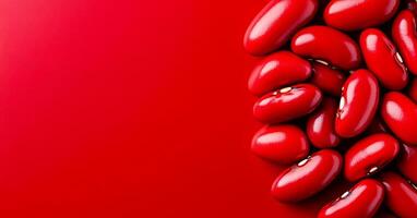 Red kidney beans on a bright background. Red kidney beans are scattered across a vibrant red surface, highlighting their smooth and shiny texture. photo