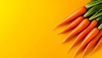 Carrots on yellow backdrop. Freshly harvested carrots with green tops lie in an appealing arrangement against a vibrant yellow backdrop. photo