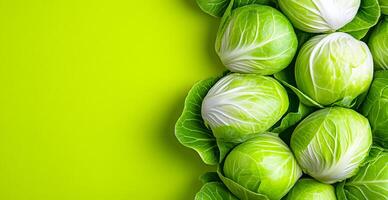 Fresh green cabbages on vibrant backdrop. Several fresh cabbages arranged neatly on a bright green background, showcasing their crisp leaves and vibrant color. photo