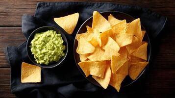 Nachos and guacamole on a black cloth on a wooden table photo