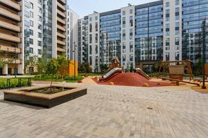 Modern playground with slides and swings in the courtyard of a new residential complex with panoramic windows. photo