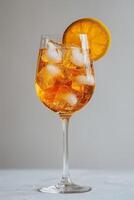 A glass of Aperol Spritz with ice and an orange slice on a thin stem, on a gray uniform background. photo