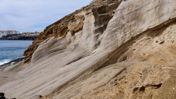 A rocky cliff with a beach in the background photo