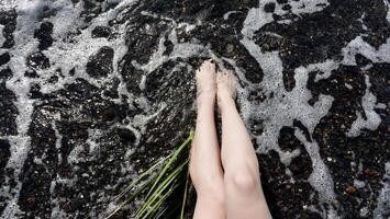 A woman's legs are in the water and she is standing on a rock photo