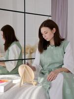 A woman sitting on a bed with a mirror behind her photo