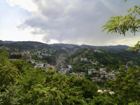 A view of a town on a hillside with trees and mountains photo