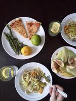 A table with plates of food and a person holding a fork photo
