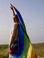A woman holding a rainbow flag in the field photo