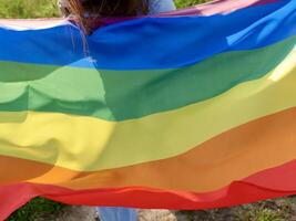 A woman holding a rainbow colored flag photo