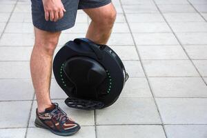 Man riding a unicycle on pavement while wearing shorts and athletic shoes near urban area photo