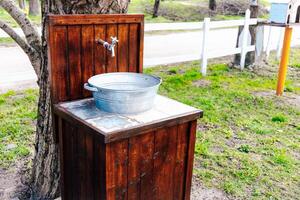 Rustic outdoor wash station with water faucet and metal basin beside a gravel path photo