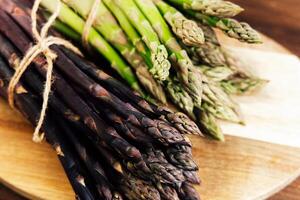 Freshly harvested asparagus varieties on a wooden cutting board in a rustic kitchen photo