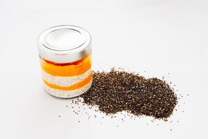 Layers of chia pudding with vibrant orange and dark topping on a clean surface photo