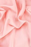 Soft pink fabric creating gentle folds and waves under bright lighting in a textile studio photo