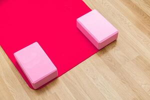 Yoga session setup with pink blocks on red mat in a bright studio environment photo