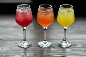 three glasses of cocktails on a dark wooden background. selective focus. photo