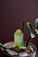 Kiwi juice in a glass with a straw and a kiwi on a wooden background photo