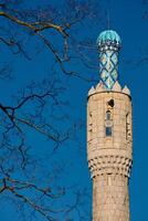 Tower of The blue dome with the golden crescent of the mosque in St.Petersburg - Russia through the branches of trees on a clear spring day photo